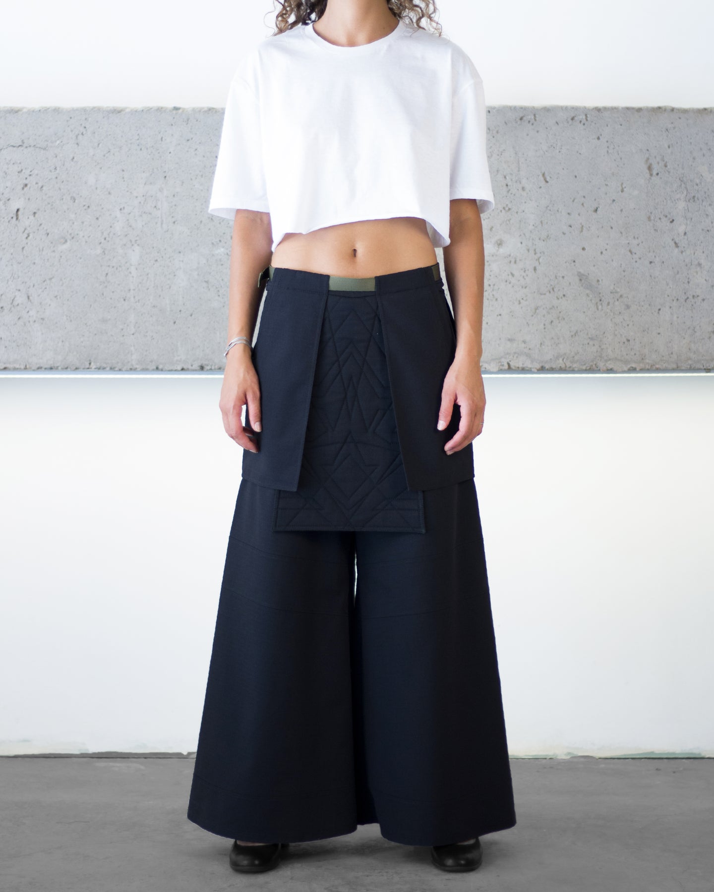 Person wearing a white top and black wide-leg pants against a plain background